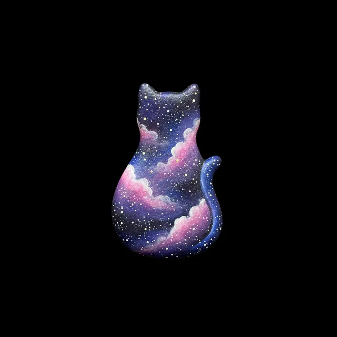 A cat shaped rock painted with a purple and blue galaxy effect