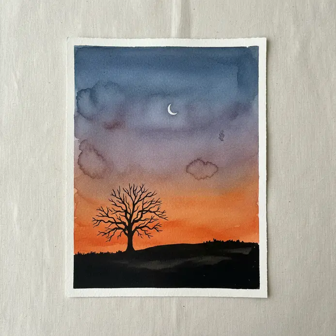 Black tree silhouette on a hill against a blended ink wash sunset with a small moon