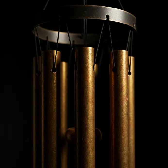 A set of brass wind chime tubes suspended from a circular ring