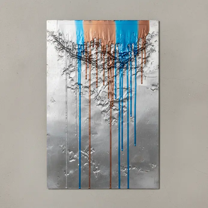 Industrial metal surface with streams of colorful melted crayon wax.