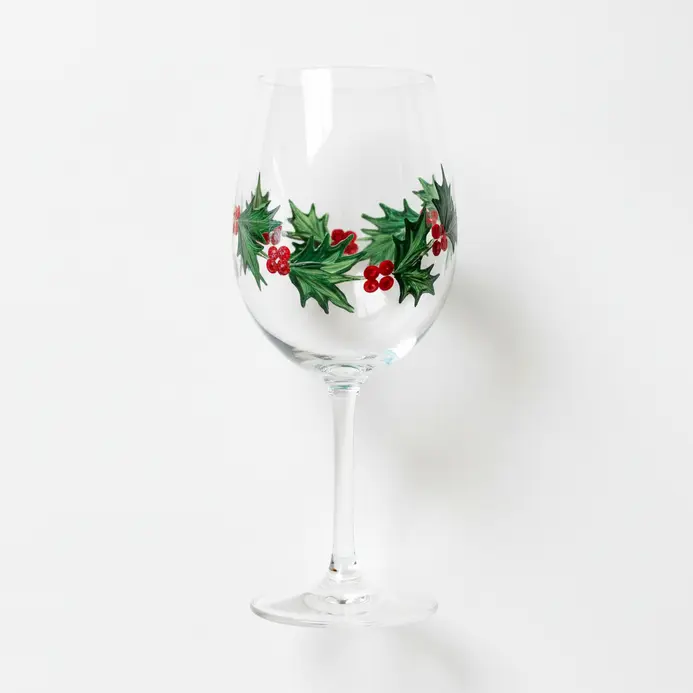 A clear wine glass sketch with a curved holly garland wrapping around the lower bowl and a few berry clusters.