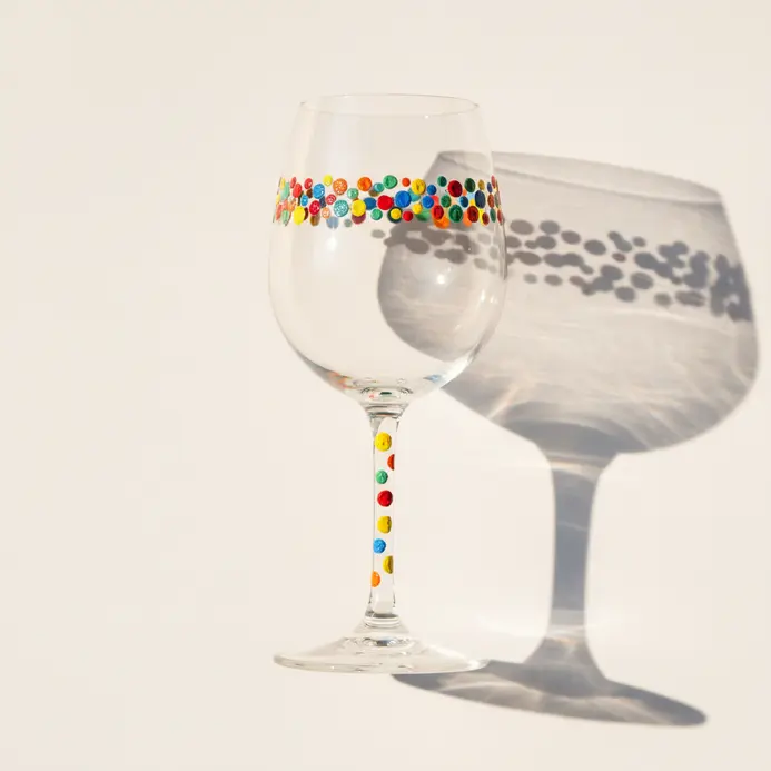 A clear wine glass sketch with small dots wrapping around the bowl in a loose band and a few dots on the stem.