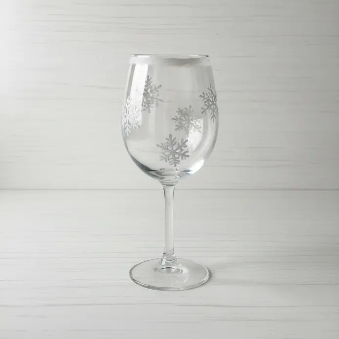 A pencil sketch of a wine glass with several spaced snowflake shapes across the bowl and a light rim detail.