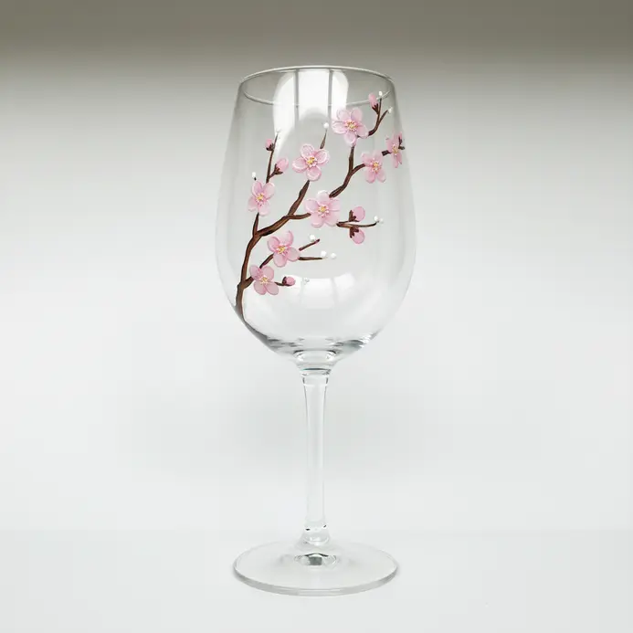 A wine glass sketch showing a curved branch with small blossoms stretching diagonally across the bowl.