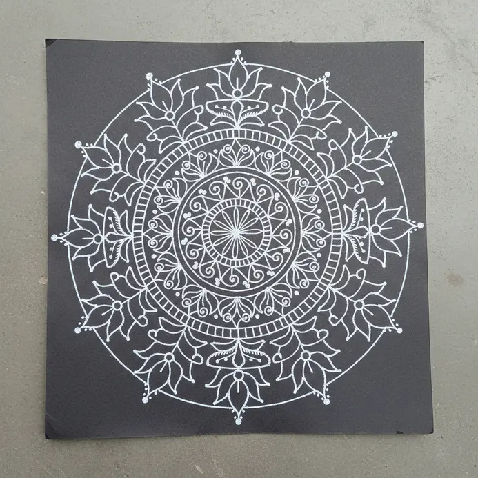 White gel pen illustration of an Alpona flower floor design pattern on dark tone paper.