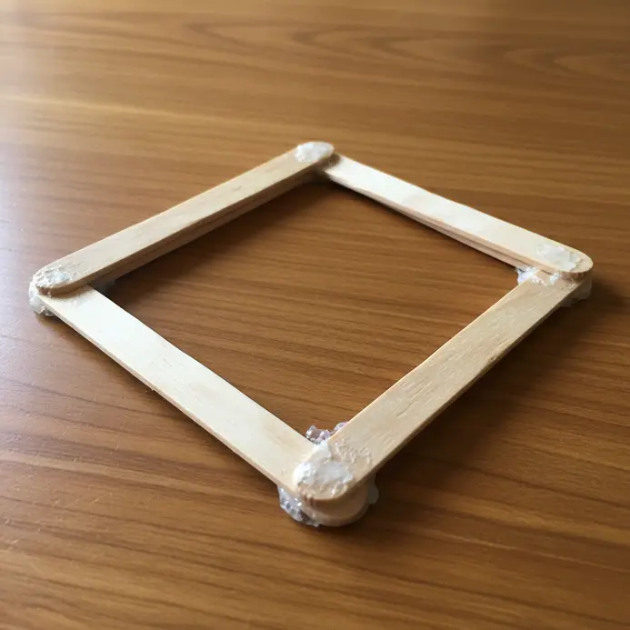 Four popsicle sticks arranged in a square shape with a photograph visible in the center.