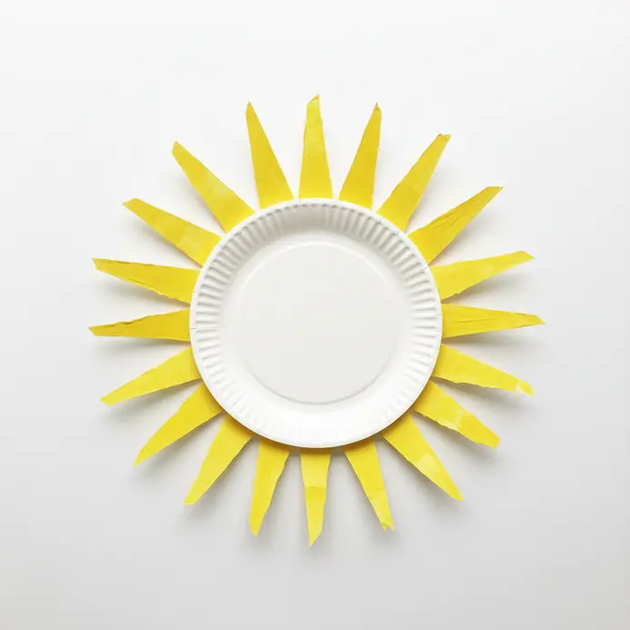 A yellow paper plate cut into a wreath shape with triangular sun rays around the border.
