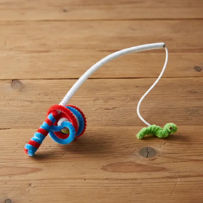 A bent brown pipe cleaner serving as a fishing pole connected to a yellow string.