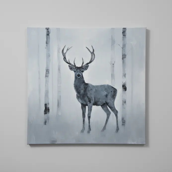 A deer silhouette with antlers standing quietly among faint, misty tree trunks in the background.