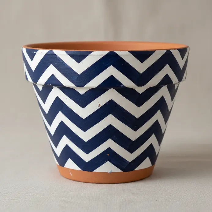 A bold, repeating navy blue chevron pattern is painted on a clay pot.