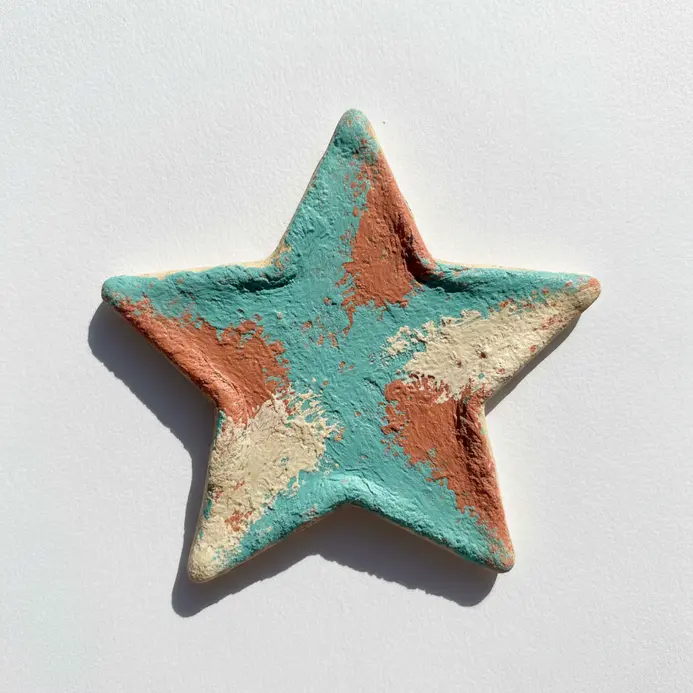 A handmade star-shaped pendant crafted from baked salt dough and painted with bright colors.