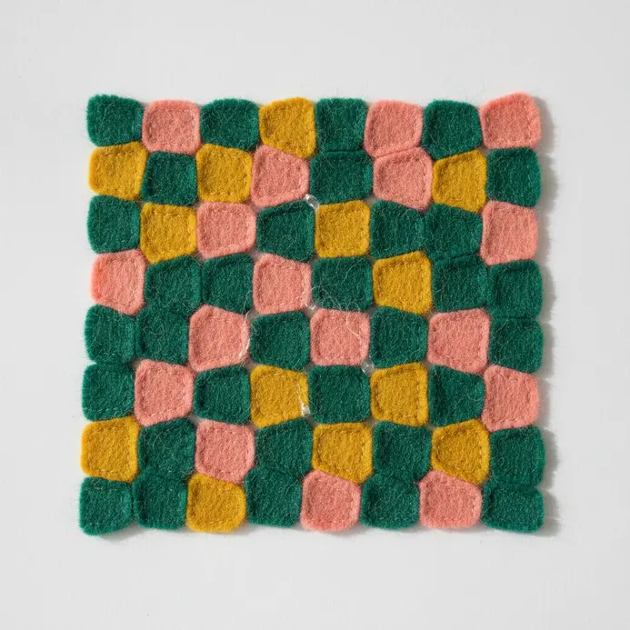 A colorful mosaic artwork made by gluing assorted felt scraps onto a fabric background.