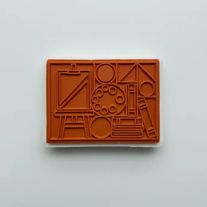 A minimalist geometric pattern carved into a pink rubber block, ready for ink.