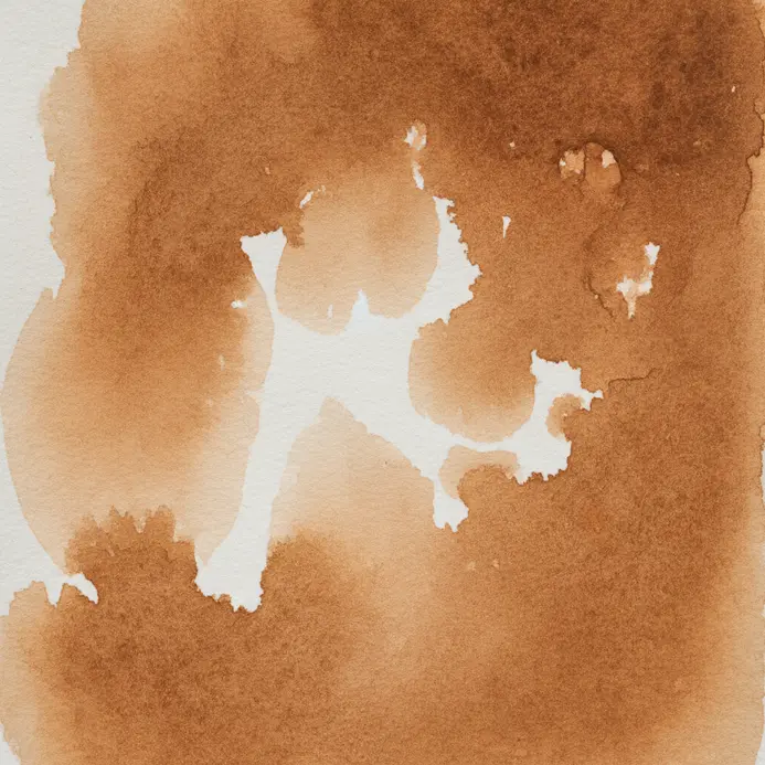 A damp brush lifts a line of wet blue watercolor paint from the surface of the paper.