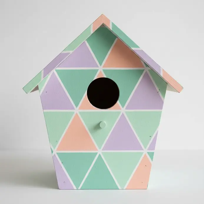 Mint, peach, and lavender triangles form a geometric pattern on a birdhouse.