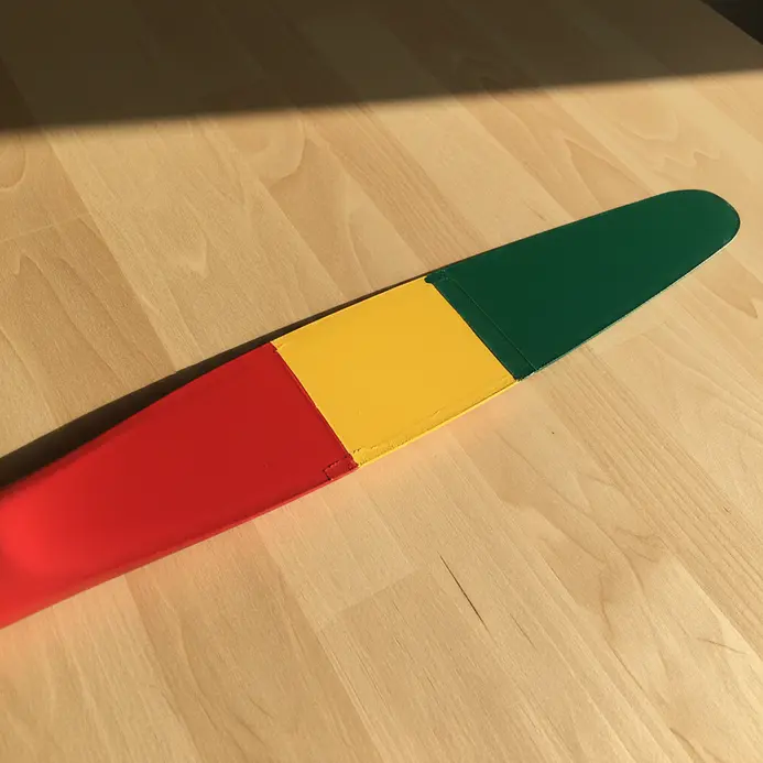 A white fan blade segmented into distinct, sharp-edged sections painted in solid red, orange, yellow, green, and blue.