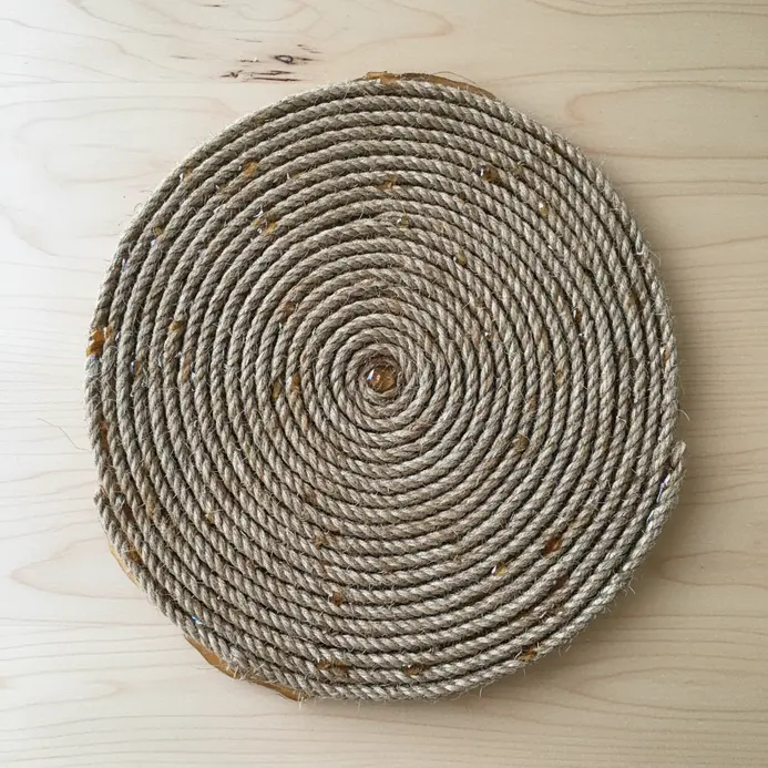 A ceiling fan blade completely covered in coiled natural jute rope secured with strong adhesive.