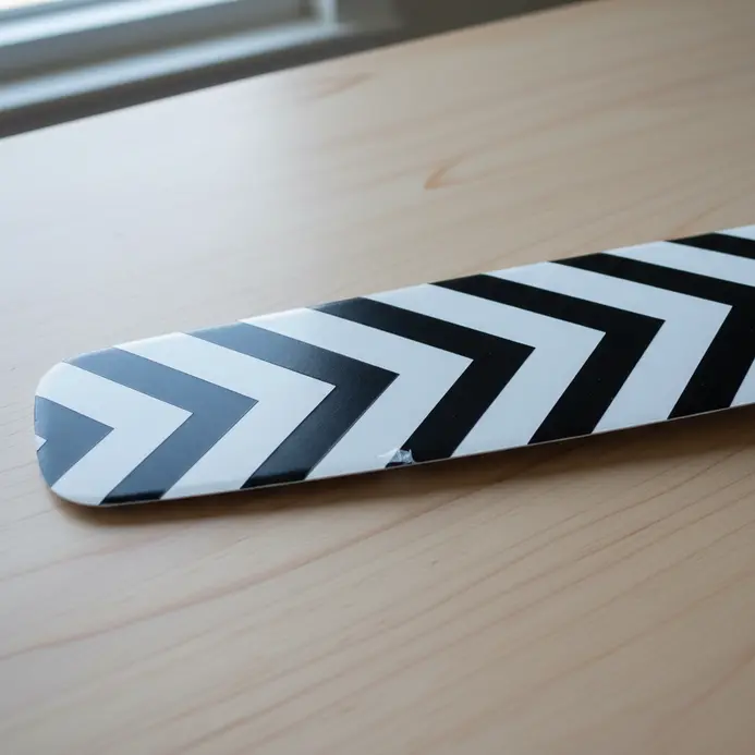 A white fan blade featuring a large, crisp black chevron pattern made from adhesive vinyl.