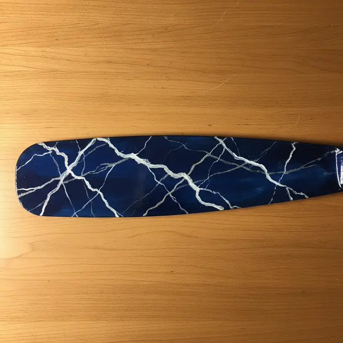 A dark blue fan blade with white veining painted to mimic the look of natural marble.