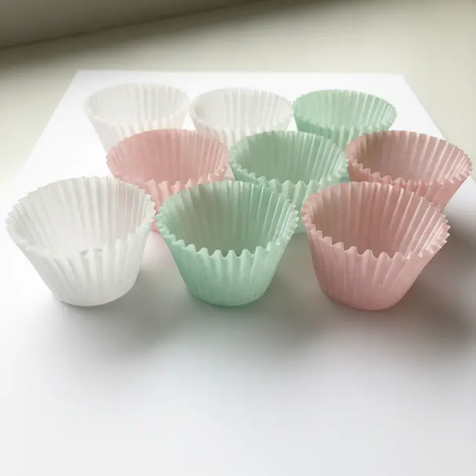 White paper doilies shaped into frilled wrappers holding frosted cupcakes.