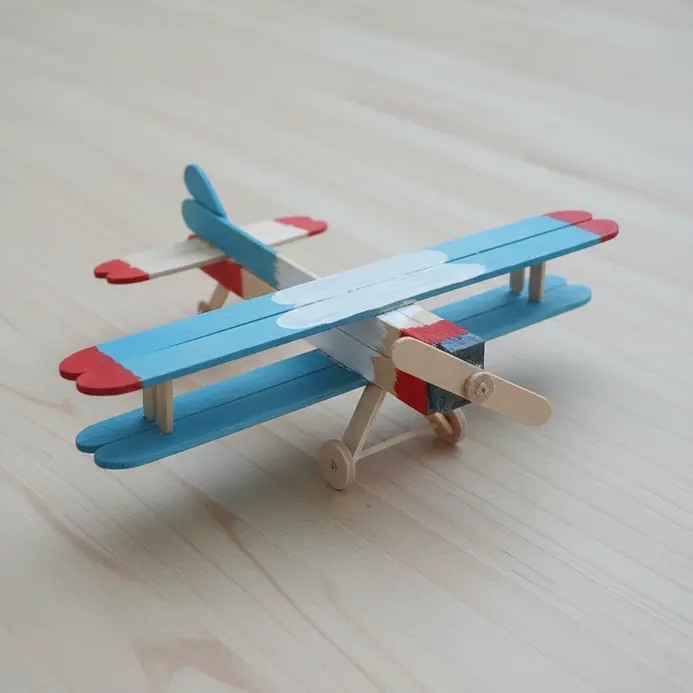 A model airplane constructed from popsicle sticks for the fuselage and wings, painted in primary colors.
