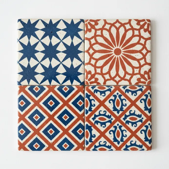 Four square ceramic tiles painted with different Indian textile-inspired geometric patterns.