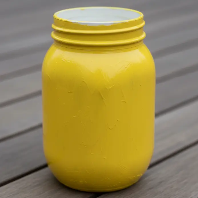 A jar coated in a solid, opaque shade of bright sunny yellow.