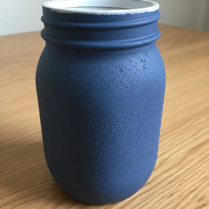 A mason jar coated in a flat, chalky navy blue paint with a textured matte finish.