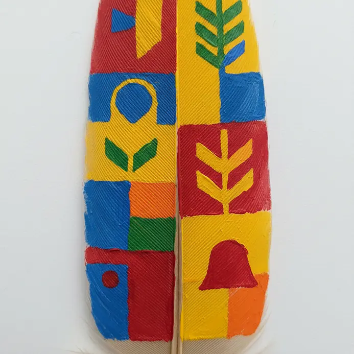 A feather painted with a repeating bold chevron pattern in classic primary colors.