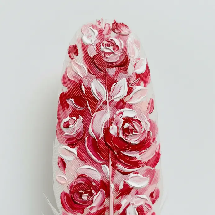 The tip of a white feather features a simple, bold heart shape painted in bright red.