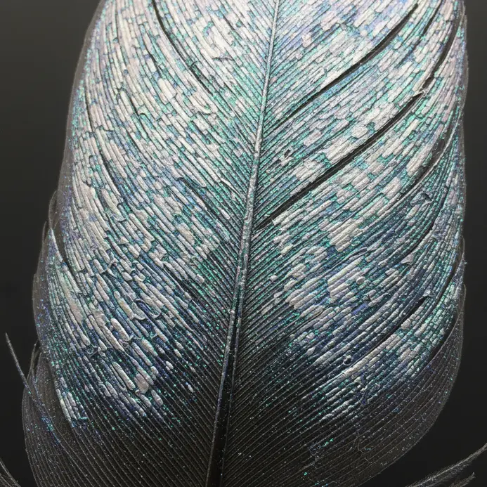A feather painted with the intricate, cell-like pattern of a dragonfly wing using iridescent paints.