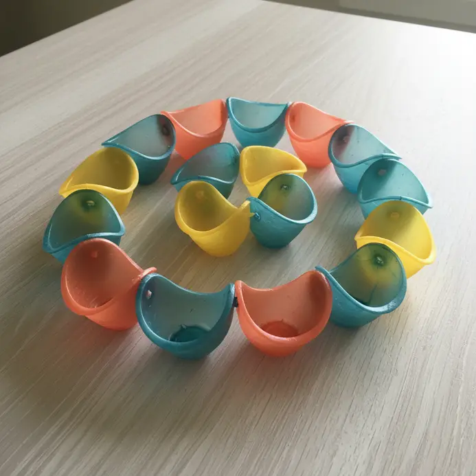 A chain of interconnected, colorful plastic bottle cups designed to guide rainwater down from a gutter.
