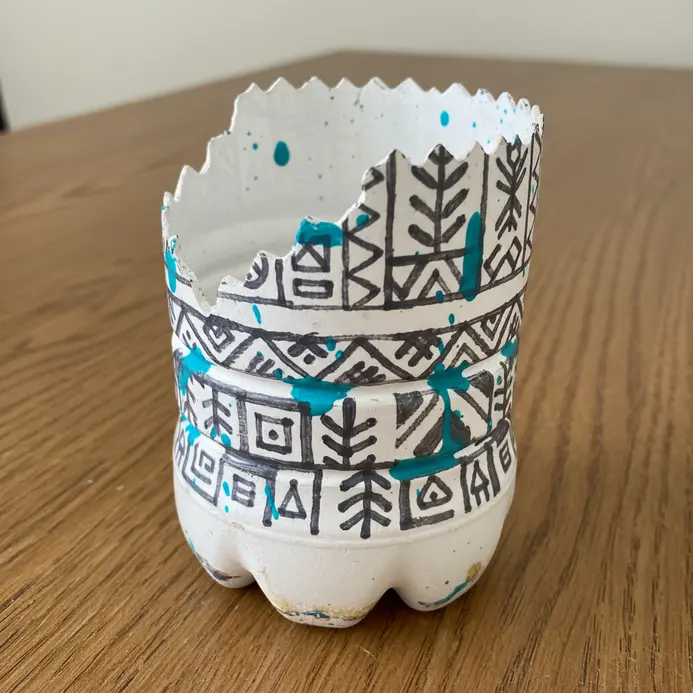 A large plastic bottle bin with a stenciled geometric or floral pattern painted on its side.