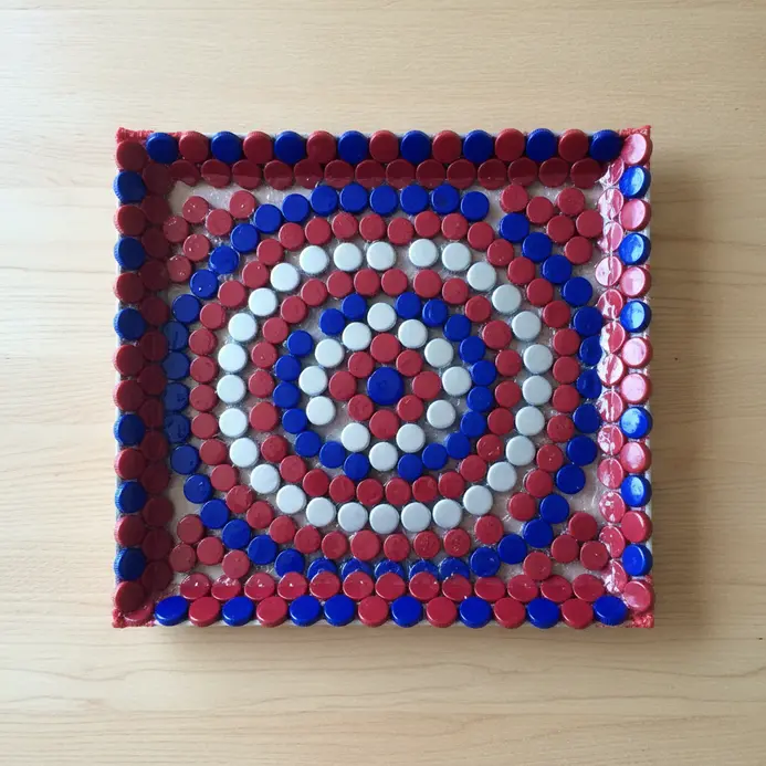 A flat serving tray with a colorful mosaic pattern made from assorted plastic bottle caps.