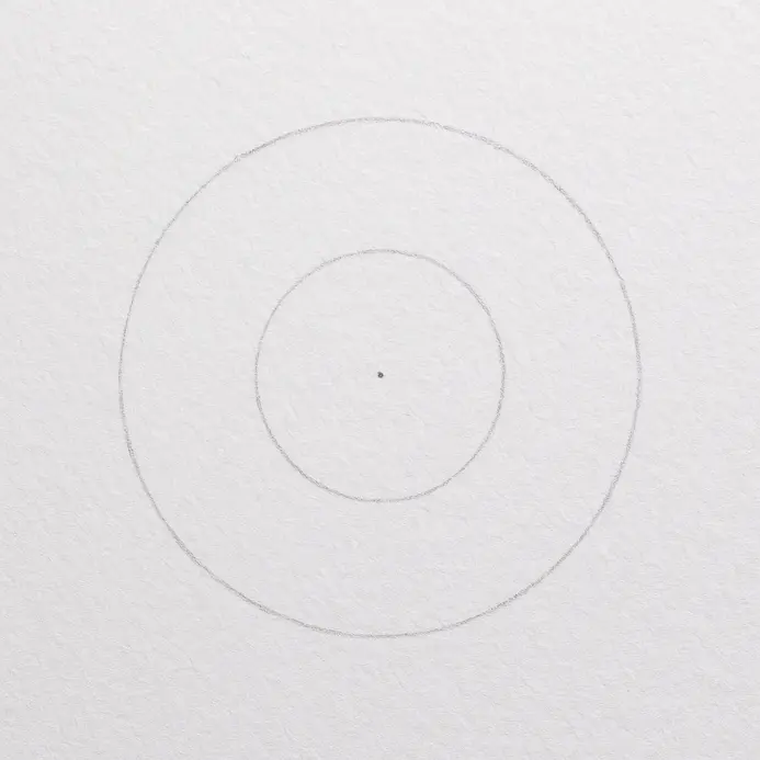 A pencil sketch showing two light concentric circles on a white paper, establishing the center of the sunflower.