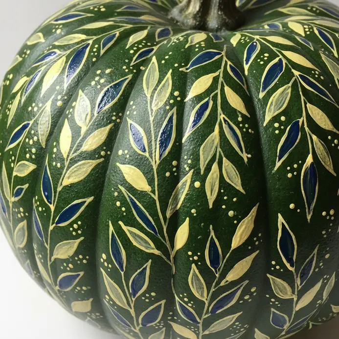 A fine-tipped brush applies a tiny dot of white paint to the edge of a green painted leaf.