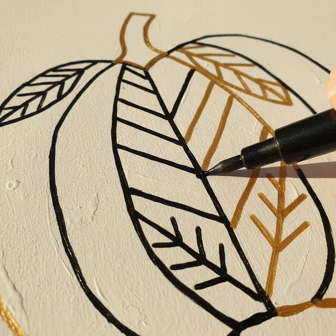 A black paint pen traces a clean, sharp outline around a gold painted star.