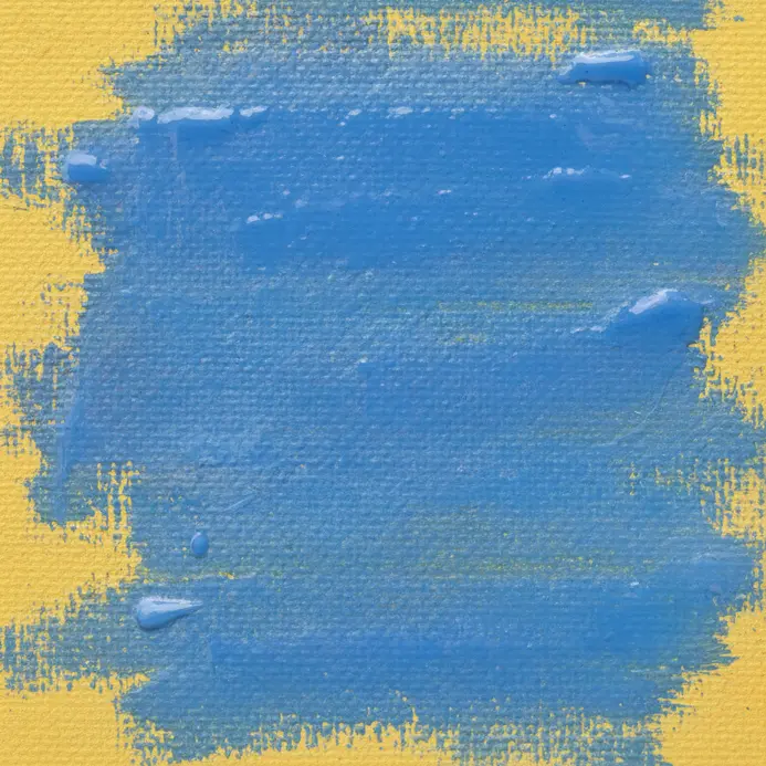A close-up of a painting where a thin blue glaze is applied over a dry yellow layer.