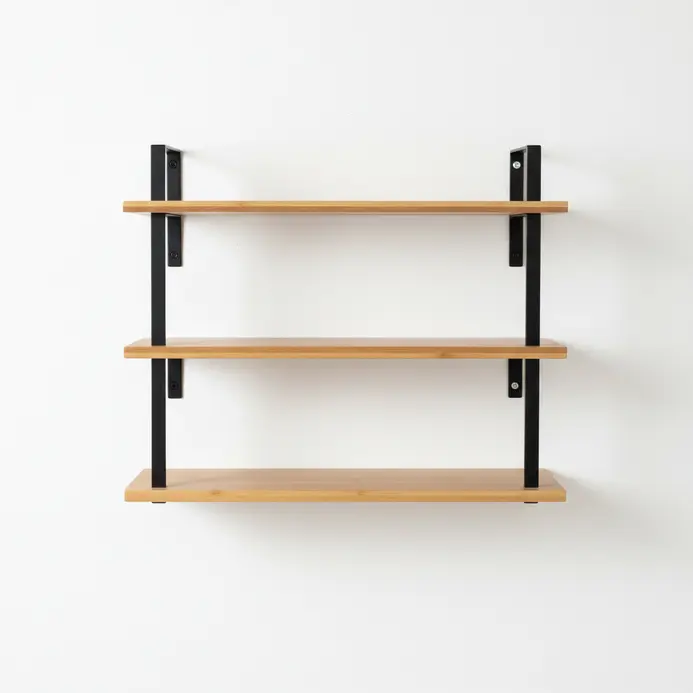 A wall-mounted shelf with three staggered bamboo shelves on simple metal brackets.