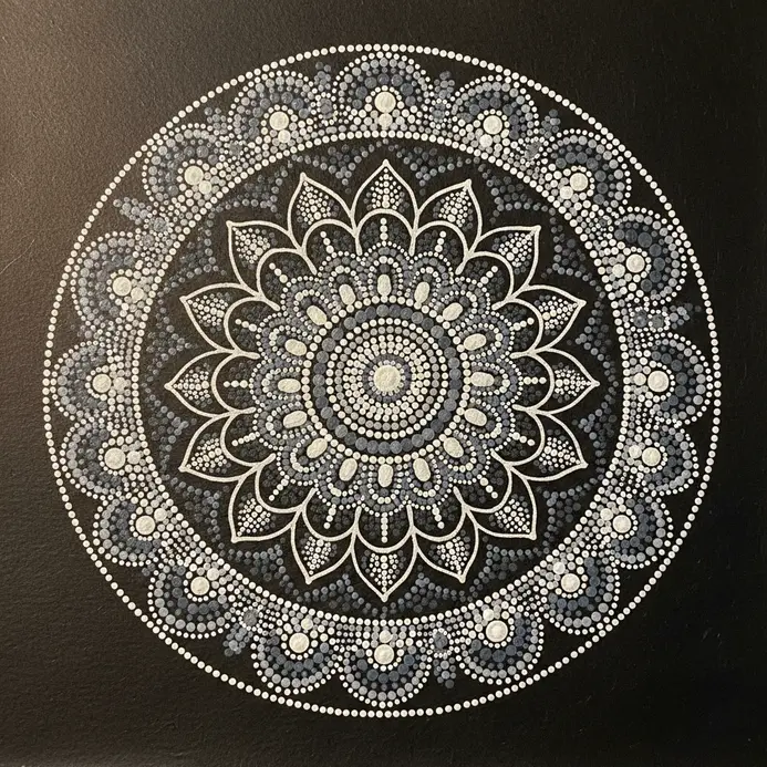 A dark mandala background with concentric rings of white dots forming petal shapes.