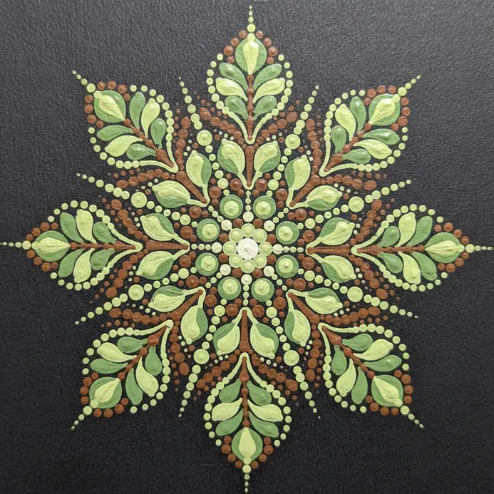 The central motif of a mandala is a perfectly symmetrical arrangement of leaves, each formed from dots.