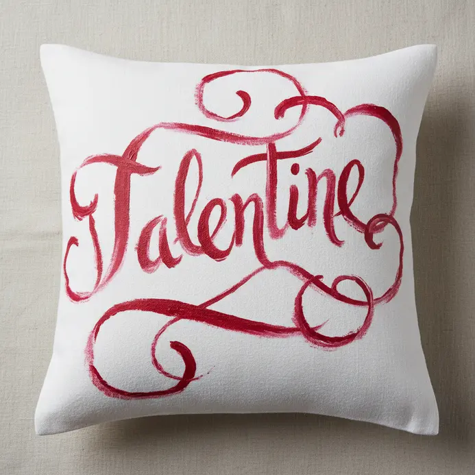 A plain white cotton pillowcase personalized with a romantic phrase painted in red fabric paint using a script font.