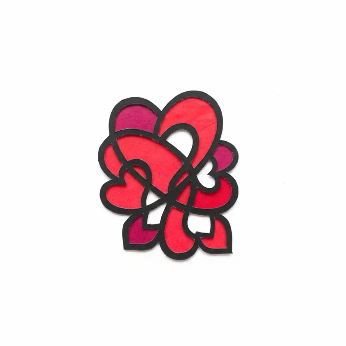 A heart-shaped suncatcher made with a black cardstock frame filled with pieces of red and pink tissue paper.