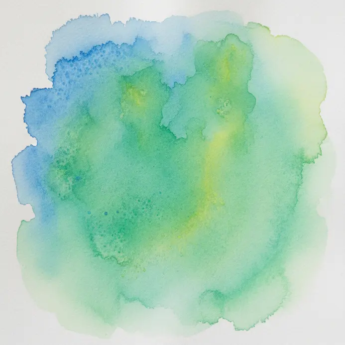 Blue and yellow watercolor pigments merging into soft green on a damp paper surface.
