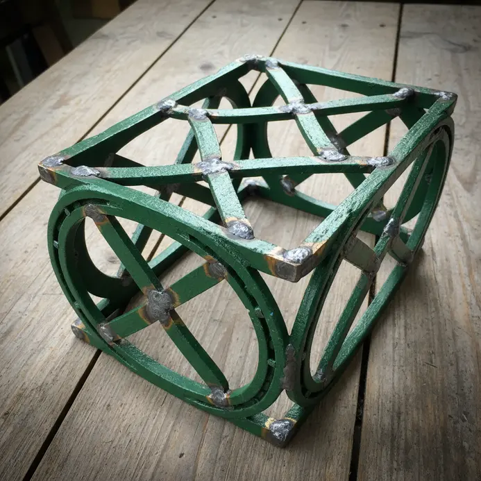 A garden trellis frame welded from horseshoes, supporting climbing vines with a rustic metal finish.