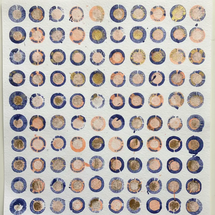 A sheet of paper is covered in a pattern created by 100 individual pencil eraser stamps.