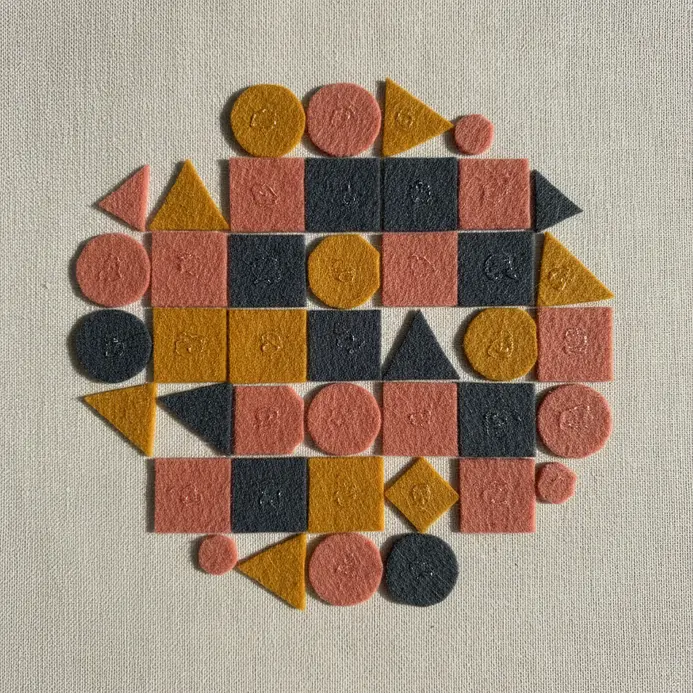 A large felt board is covered with a collage of 100 different colored felt shapes.