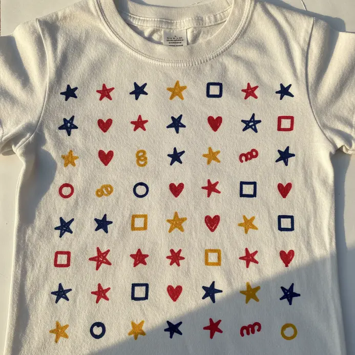 A white t-shirt displays a collection of 100 tiny drawings made with fabric markers.