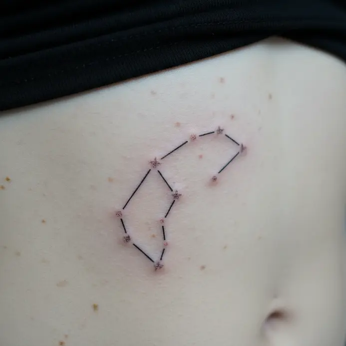 A fine-line Aries constellation tattoo placed delicately along the underboob or rib cage area.
