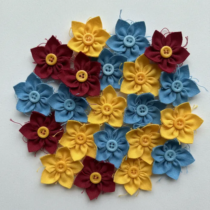 A cluster of brightly colored fabric flowers, each with a contrasting button sewn at its center.